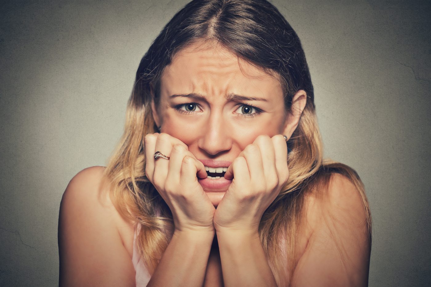 nervous stressed young woman biting fingernails looking anxiously craving Closeup portrait headshot nervous stressed young woman girl student biting fingernails looking anxiously craving something isolated grey wall background. Human emotion face expression feeling